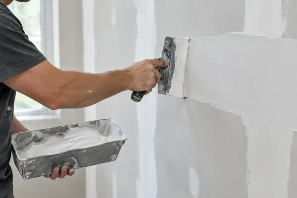 Skim coating a drywall wall with a taping knife